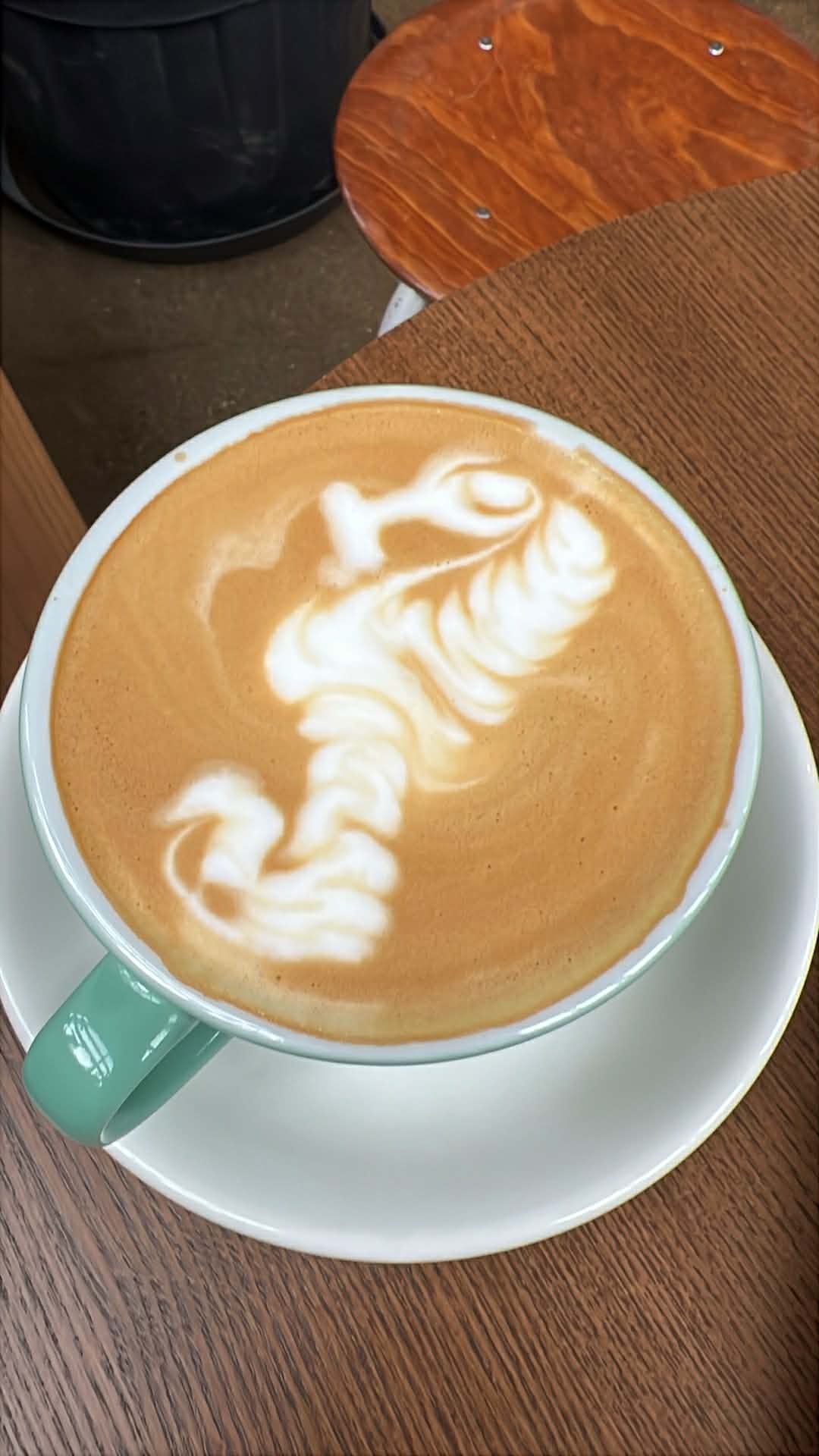 Latte art scorpion design in a mint green cup